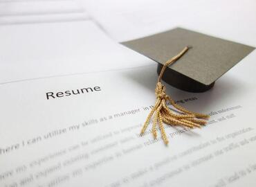 Image of Mini Paper Graduation Hat on a Paper Resume. Photo Credits: Times Higher Education